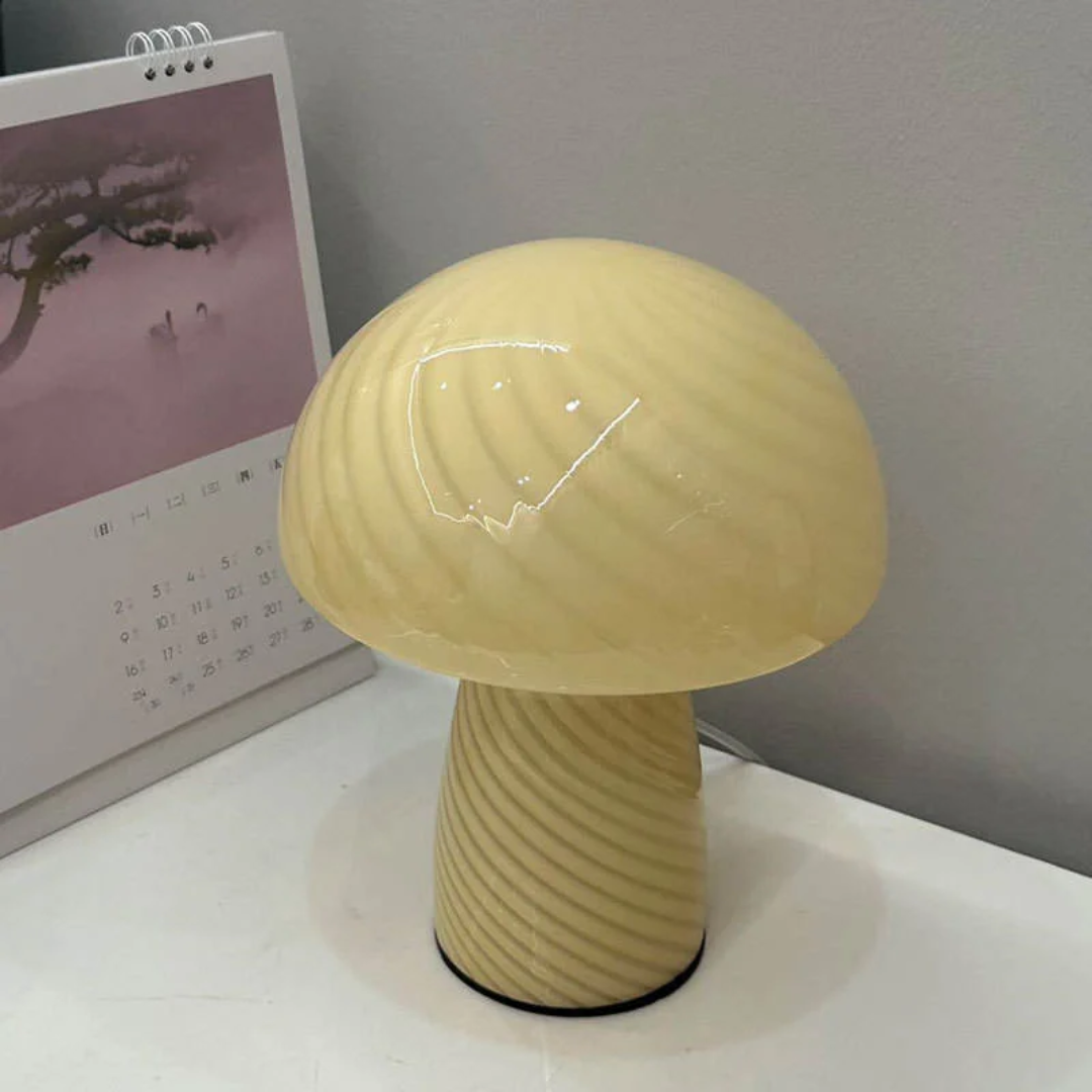 Cream colored mushroom glass table lamp with swirled pattern on a white desk