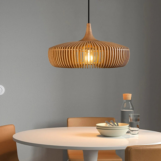 Wooden pendant light hanging above a dining table with chairs against a gray wall.