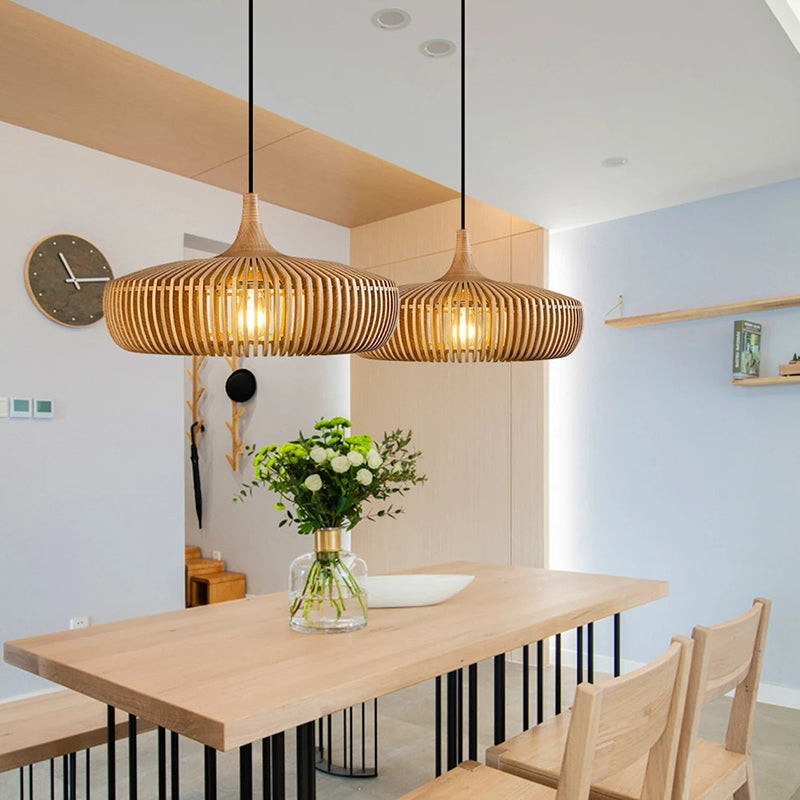 round pendant light made of vertical wooden slats hanging over a white dining table.