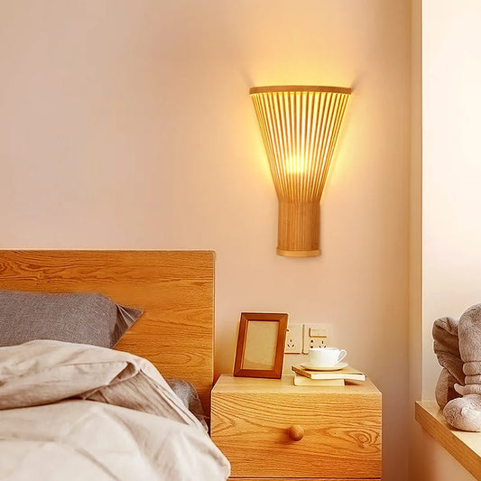 Bamboo slat Japanese wall sconce casting warm light on a light neutral bedroom wall.