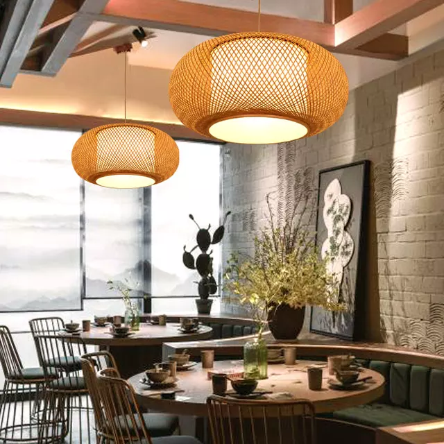 Modern restaurant interior with wicker pendant lights, round tables, and decorative elements.