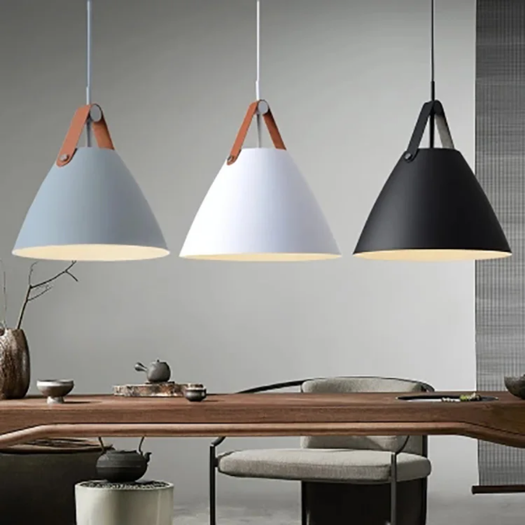 Three cone shaped pendant lights in grey white and black with leather strap details hanging over a wooden table.