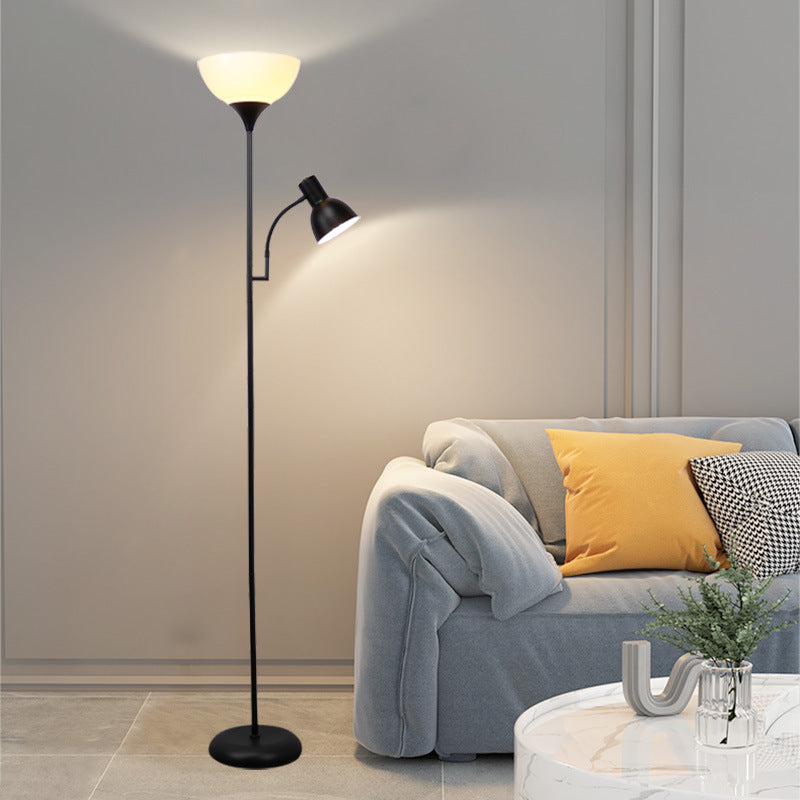 A black floor lamp with an uplighter and a small adjustable side reading light next to a grey sofa.