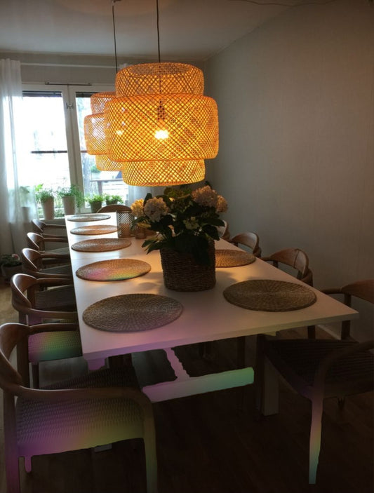 Handwoven Sinnerlig bamboo pendant lamp displaying a warm glow through a lattice shade over a wooden dining table.
