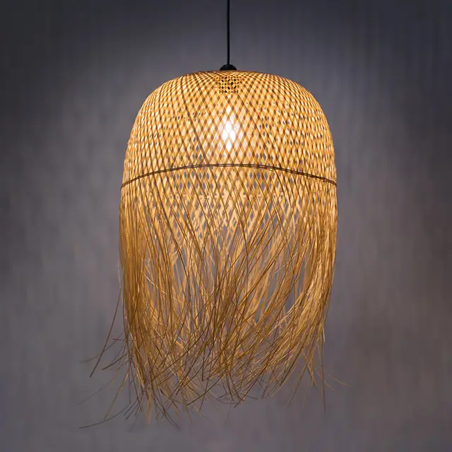 Natural woven bamboo dome pendant light fixture with fringed bottom edge hanging against a grey background.