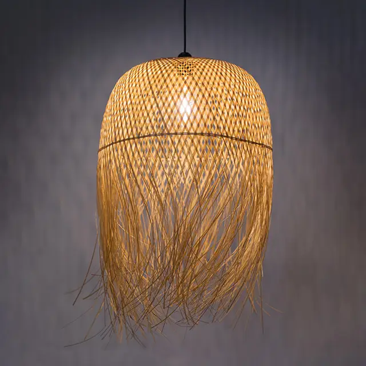 Natural woven bamboo dome pendant light fixture with fringed bottom edge hanging against a grey background.