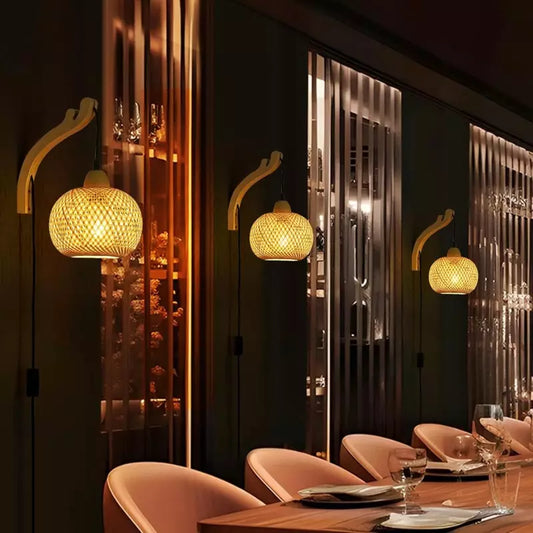 A wall-mounted wooden sconce with a a round woven bamboo lampshade with a black cord.